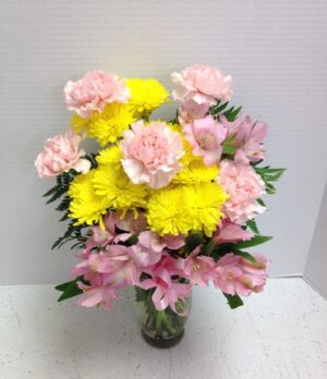 yellow and pink carnations in clear vase